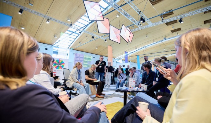 Besucher der New Work Evolution sitzen in einem Kreis und hören gespannt einem Vortrag zu.