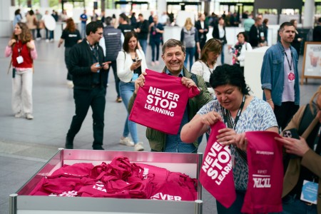An exhibitor hands a LEARNTEC exhibition bag to a visitor. 