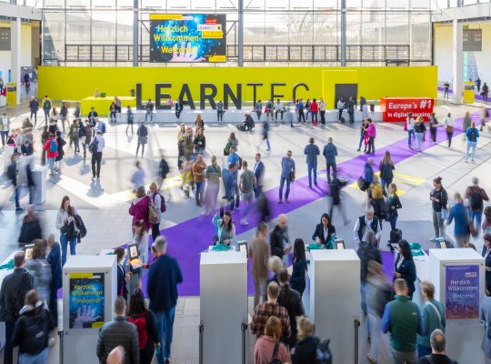 Eingang der Messe / Aktionshalle mit Besuchenden und LEARNTEC-Schriftzug