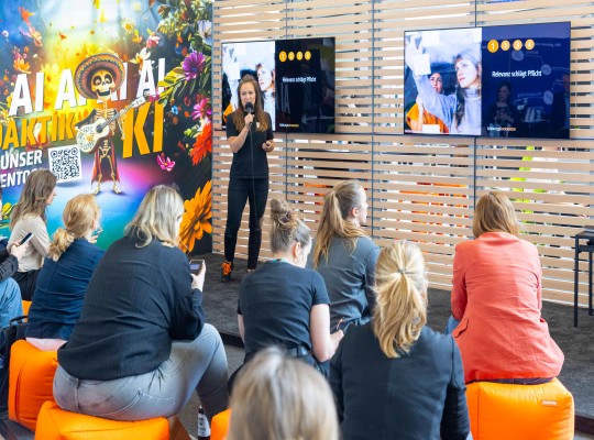 Eine Gruppe von Besuchenden hört sich einen Vortrag am Messestand an