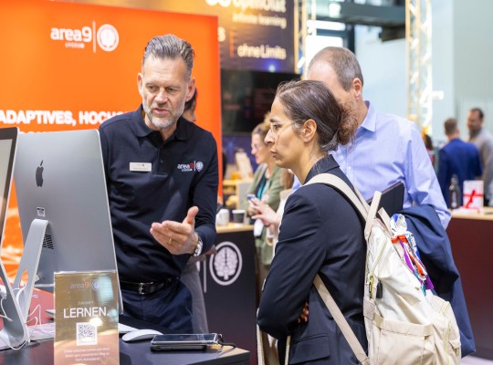 Besuchende lassen sich an einem Messestand Software-Lösungen erklären